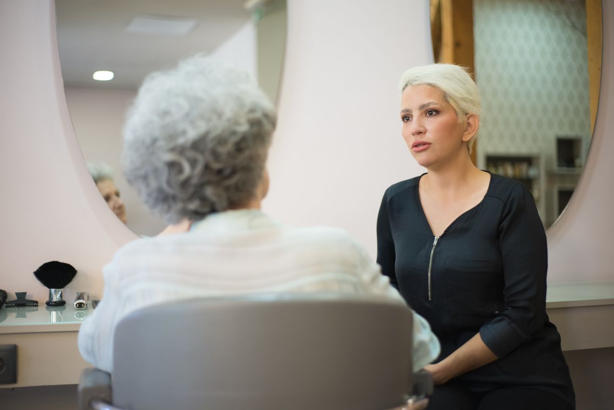 Coiffeuse en conversation avec sa cliente devant le miroir