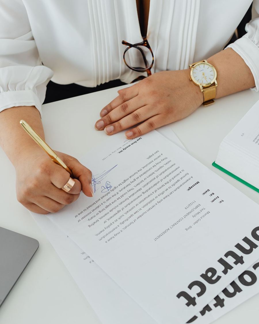 Une personne relit et signe un contrat sur un bureau